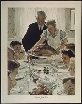 A large family gathered at a table for a holiday meal as the turkey arrives at the table.