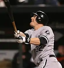 Brian Anderson following through on his swing, looking towards the left and the ball (offscreen) he has just hit. He is playing for the Chicago White Sox.