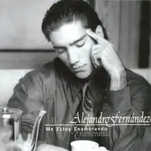 A black-and-white photo of a man wearing a suit sitting down next to a table.