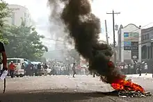 A fire burns as protesters stand in the background