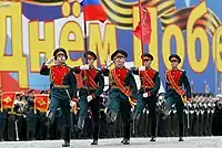 Honour guard marching with the Russian flag and the Victory Banner