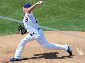 A man in a white baseball uniform and blue cap