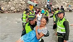 Colombian refugee being carried by Colombian National Police across the river into Colombia