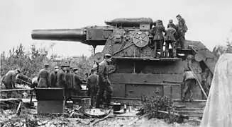 A massive short-barrelled gun being reloaded by its large crew