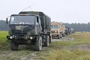 M1078 A1R (front), with an Oshkosh-produced M1083 A1P2 in A-kit configuration immediately behind