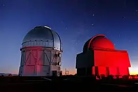 The towering Víctor M. Blanco 4-meter Telescope and one of the four SMARTS Consortium telescopes, both set against the spectacular backdrop of the early evening sky