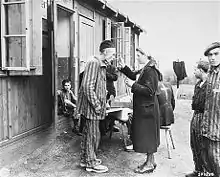 Liberated Neuengamme survivor standing on the right has a triangle patch with a top-bar