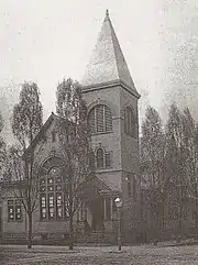 Old church with a large spire on a tree-lined corner