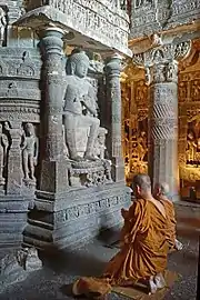 Buddhist monks praying in front of the Dagoba of Chaitya Cave 26 of the Ajanta Caves.