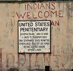 A sign that reads United States Penitentiary has graffiti above it saying "Indians Welcome".