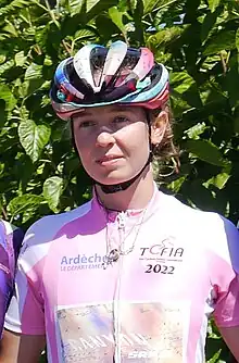 White woman in a pink top and helmet.