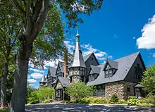 Cobblestone building with steeple and chimney, surrounded by shrubbery