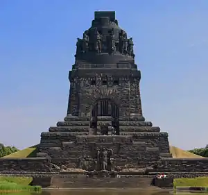 monument commemorating the battle, tall square block, soldier on top, images of soldiers around the monument