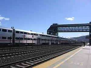 A train at a station with a large footbridge