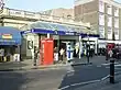 A white-bricked building with a clear, sloped roof and a sign that reads "BAYSWATER STATION" in white letters on a blue background