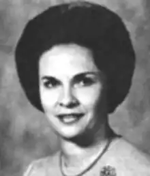 A smiling fair-skinned woman with dark hair in a bouffant style