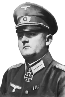 A man wearing a peaked cap and military uniform with an Iron Cross displayed at the front of his uniform collar.