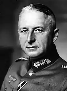 Black-and-white portrait of an older man wearing a military uniform, his hair is combed back.