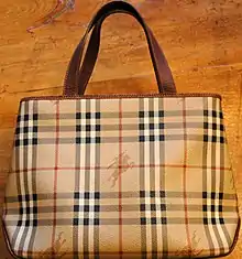 A purse in the tan, black, and white Burberry check pattern, with rearing-horseman logos superimposed