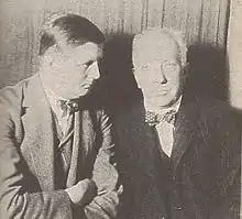  young man sitting with older, balding moustached man