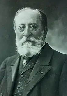 bust-length portrait of Saint-Saëns with a beard in a vest and suit, looking at the viewer