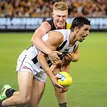 A player attempts to stop his opponent from disposing of a ball by wrapping his arms around the opponent's chest