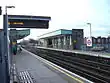 A railway platform with a railway track running through it from the left portion of the background to the right portion of the foreground