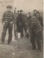 Charlie Hunter (left) watches as Old Tom Morris plays a shot in 1863 at Prestwick. Both of the players are wearing the traditional tweeds.