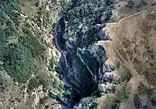 Looking down into the gorge with a road with cars on it running from the top to the bottom of the picture. To the left are less steep slopes covered in vegetation.