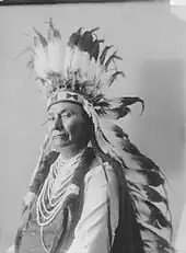 A portrait of Chief Joseph facing left, wearing a feathered headdress.