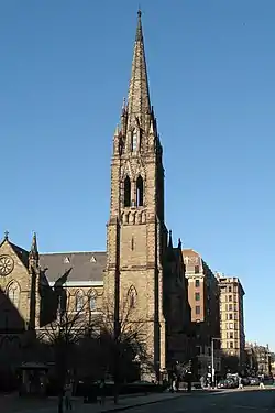 Ground-level view of a Gothic-style cathedral with a prominent, ornate steeple on one end