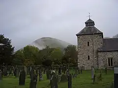 Church tower at Pennant Melangell with the breast-shaped hill in the background