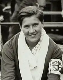 A young white woman with short dark hair, smiling, with a towel over her shoulders.