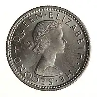 A silver-colored New Zealand sixpence with a portrait of Queen Elizabeth II.