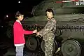 The first signs of support. A teenager hands a rose to a soldier at a M41 Walker Bulldog light tank.