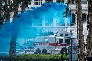 Police using a dyed water cannon to disperse protesters from the road