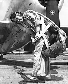 Woman standing in front of an aeroplane wearing a flight suit