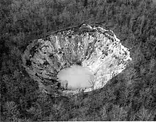 More than three acres of trees are missing in a forest after collapsing into a funnel shaped pit with water at the bottom.