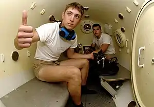 Two United States Navy sailors inside a decompression chamber about to undergo training