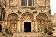 Photographie d'un bas de façade d'église avec trois arcades romanes