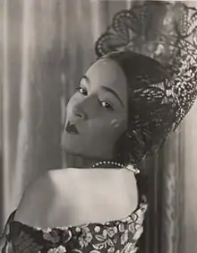 Del Río wearing what it seems to be a crown while being with her back turned and looking right in front of a camera