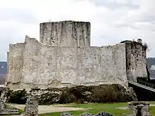 A photograph of a tall grey castle, with a taller keep visible beyond the main walls.