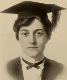 A young white woman with dark hair, wearing an academic mortarboard cap and gown