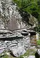 Adding a dry stone wall to convert the space under a large rock into a functional building near Bignasco, Switzerland