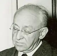 black and white headshot of an older man wearing glasses and looking downward