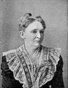 Black and white photograph of a woman wearing a dress with a large lace collar.