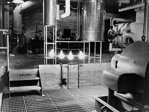 An industrial room with four large illuminated light bulbs hanging down from a bar.