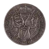 The reverse of a 1901 British Florin, featuring the heraldic shields of England, Scotland, and Ireland arranged in a triangular formation around a thistle, shamrock, and rose. A royal crown is placed above, bordered by two sceptres crossed at the centre of the shields and coin.  The date at bottom, 1901, is interrupted by the bottom of the Irish shield. Arcing around the coin at left is ONE FLORIN, while at right is TWO SHILLINGS.