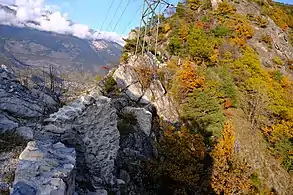 A first wall partially destroyed in the foreground and another in the background, built on a rock.