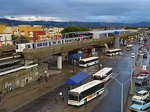 A view of the Fruitvale BART station from the west side, above ground, with train visible